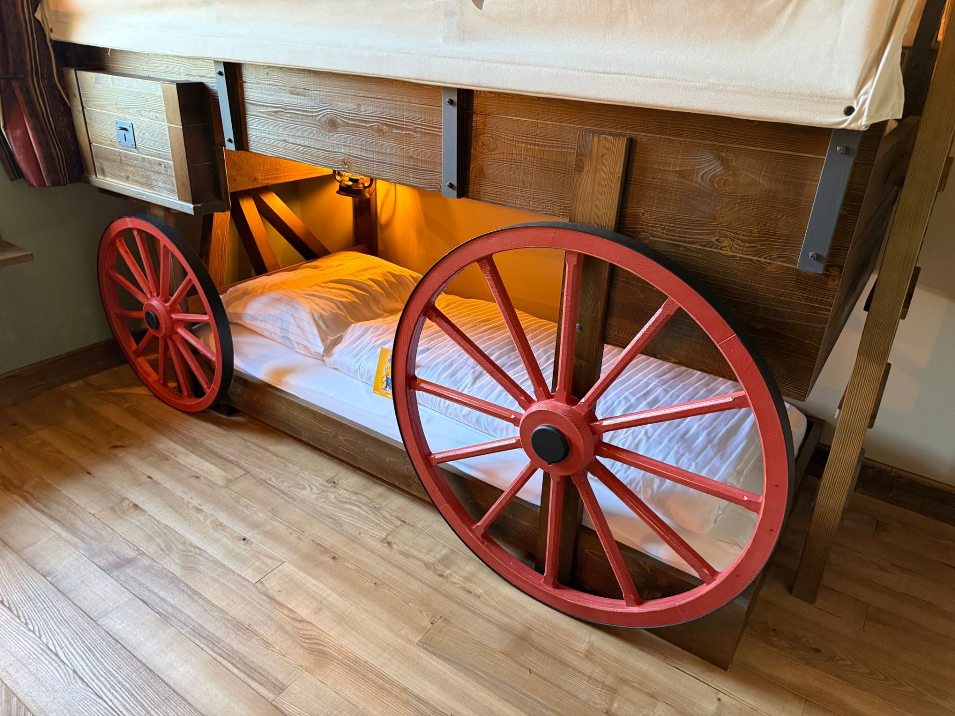 Riverside Lodge – Planwagen-Bett Detailansicht der roten Holzräder