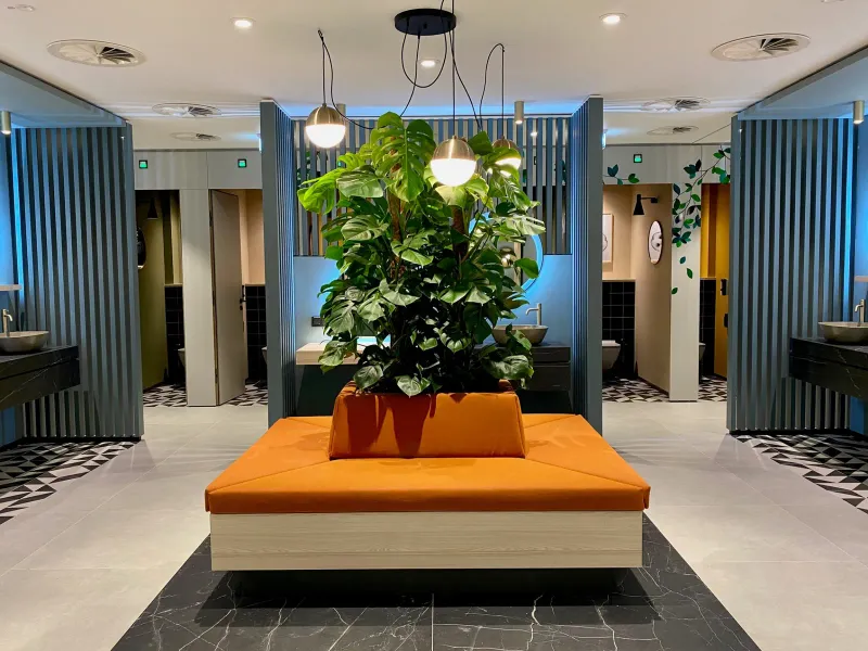 Zentraler Wartebereich mit Monstera-Pflanze und Sitzinsel