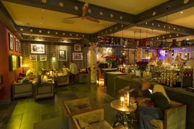 Hotelbar im Industrial-Stil mit Backsteinwand, Barhockern und Loungebereich