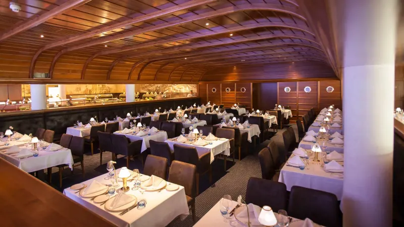 Restaurant mit gewölbter Mahagonidecke, Lederbestuhlung und Porthole-Fenstern