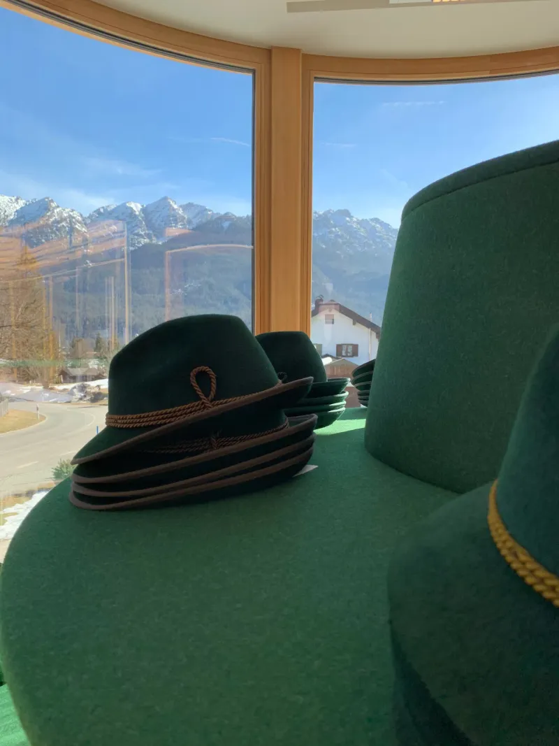 Trachtenhüte vor Panoramafenster mit Bergblick