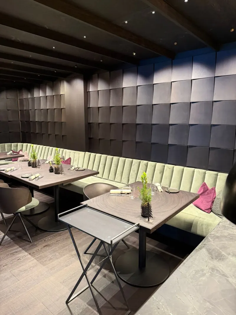 Restaurantbereich mit Schindelwand und verschiedenen Tischgrößen