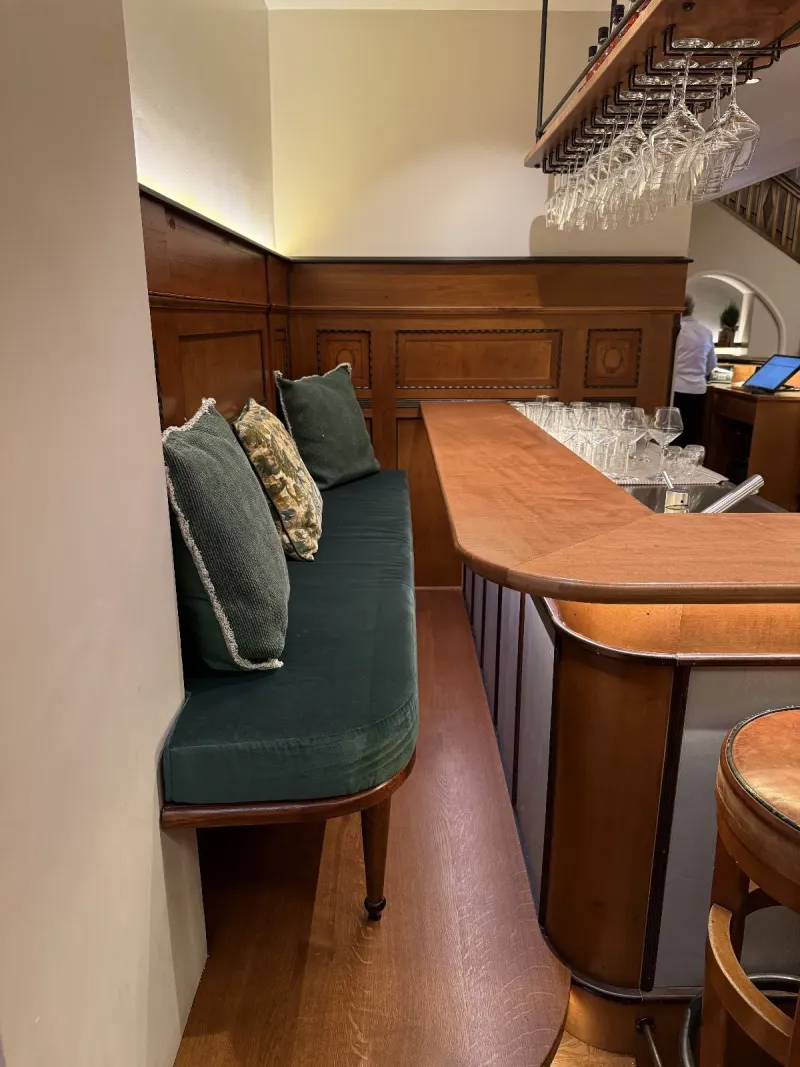 Sitzbank mit Samtpolster und Wandvertäfelung an der Bar