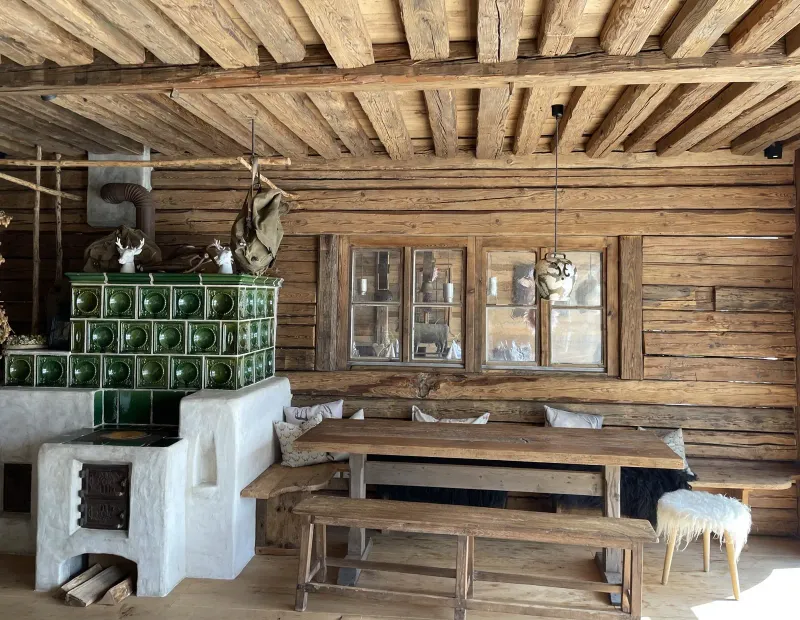Altholzdecke mit grünem Kachelofen und Holzbank